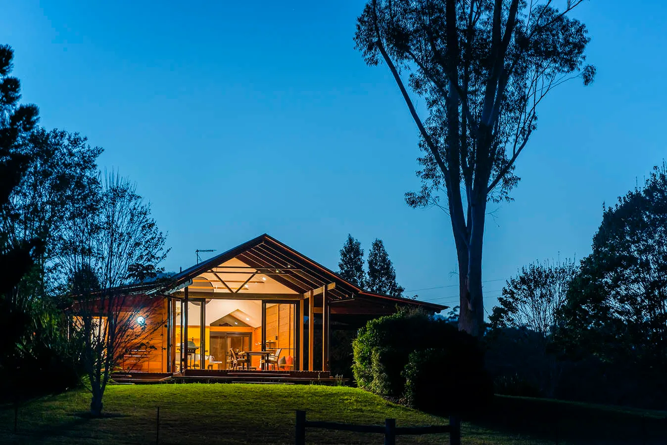 The Bower chalet glowing warmly at night, warm light spilling from timber-framed windows