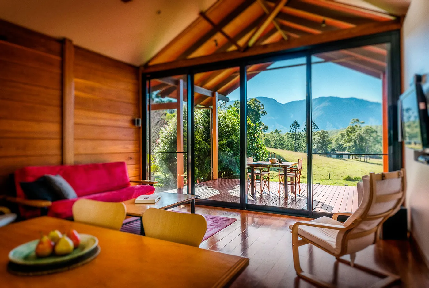 Tallowood interior — pink sofa, mountain views through floor-to-ceiling glass