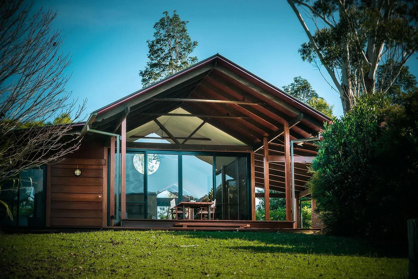 The Bower chalet — timber cladding with a round gabled window, nestled among gardens